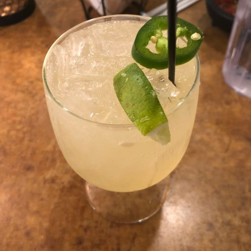 A La Olla Mexican Cafe margarita with ice, a lime wedge, and a jalapeño slice.